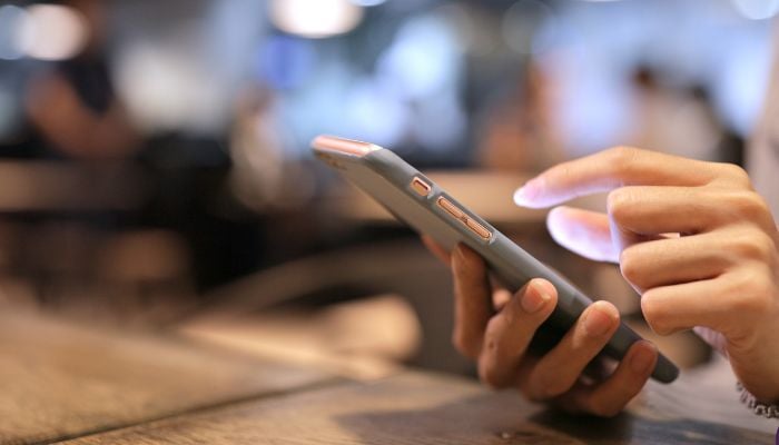 An undated image of a person using a phone. — Canva