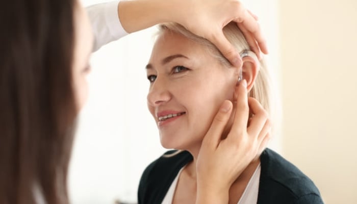 An undated image of an individual with hearing impairement using a hearing aid. — Adobe Stock
