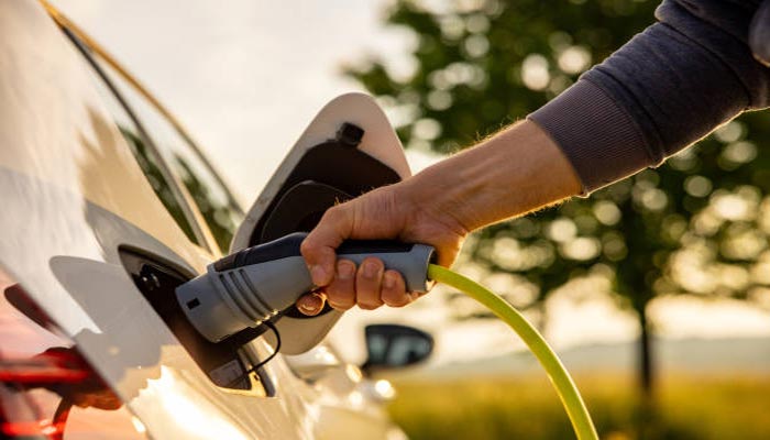 An undated image of person inserting power cord into electric car for charging. — iStock