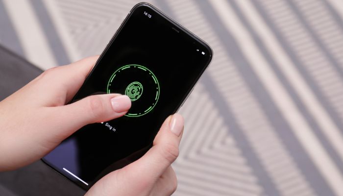 An undated image of a person unlocking a mobile through a fingerprint feature. — Canva