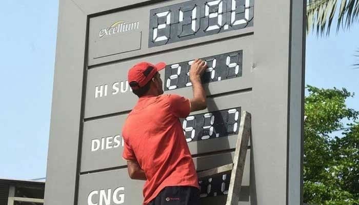 A petrol pump worker changing the price of petroleum products in this undated picture. — AFP